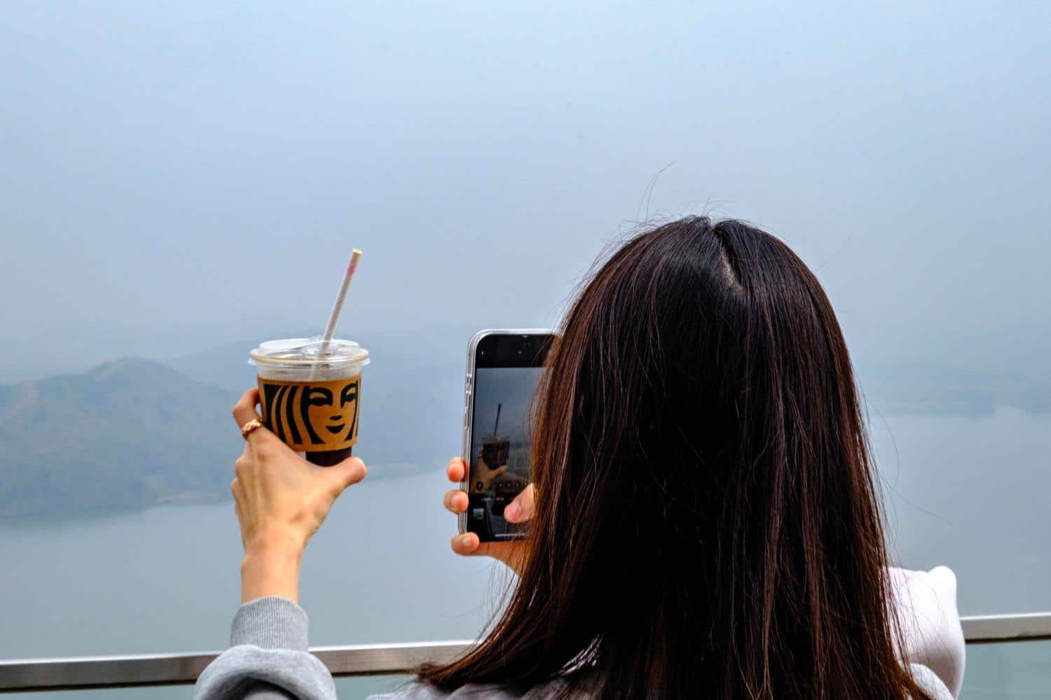 A tourist takes a picture of her Starbucks coffee with North Korea in the background at Aegibong Observatory (April 2025).