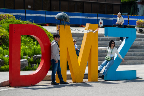 Tourists take pictures in front of a DMZ sign.