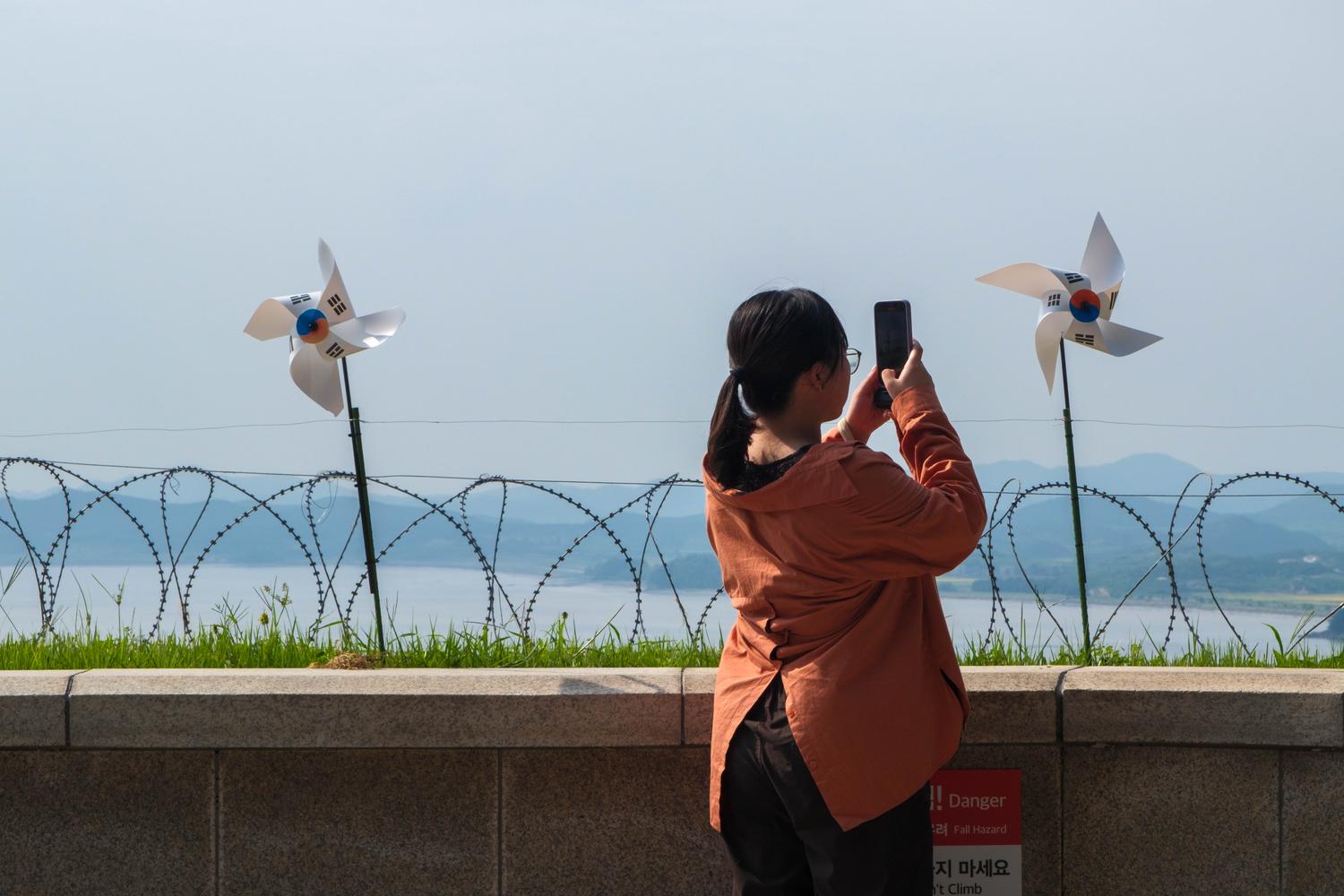 A visitor takes a picture of a South Korean flag in the shape of a windmill in front of the North Korean bank of the Han River at Odusan Observatory.